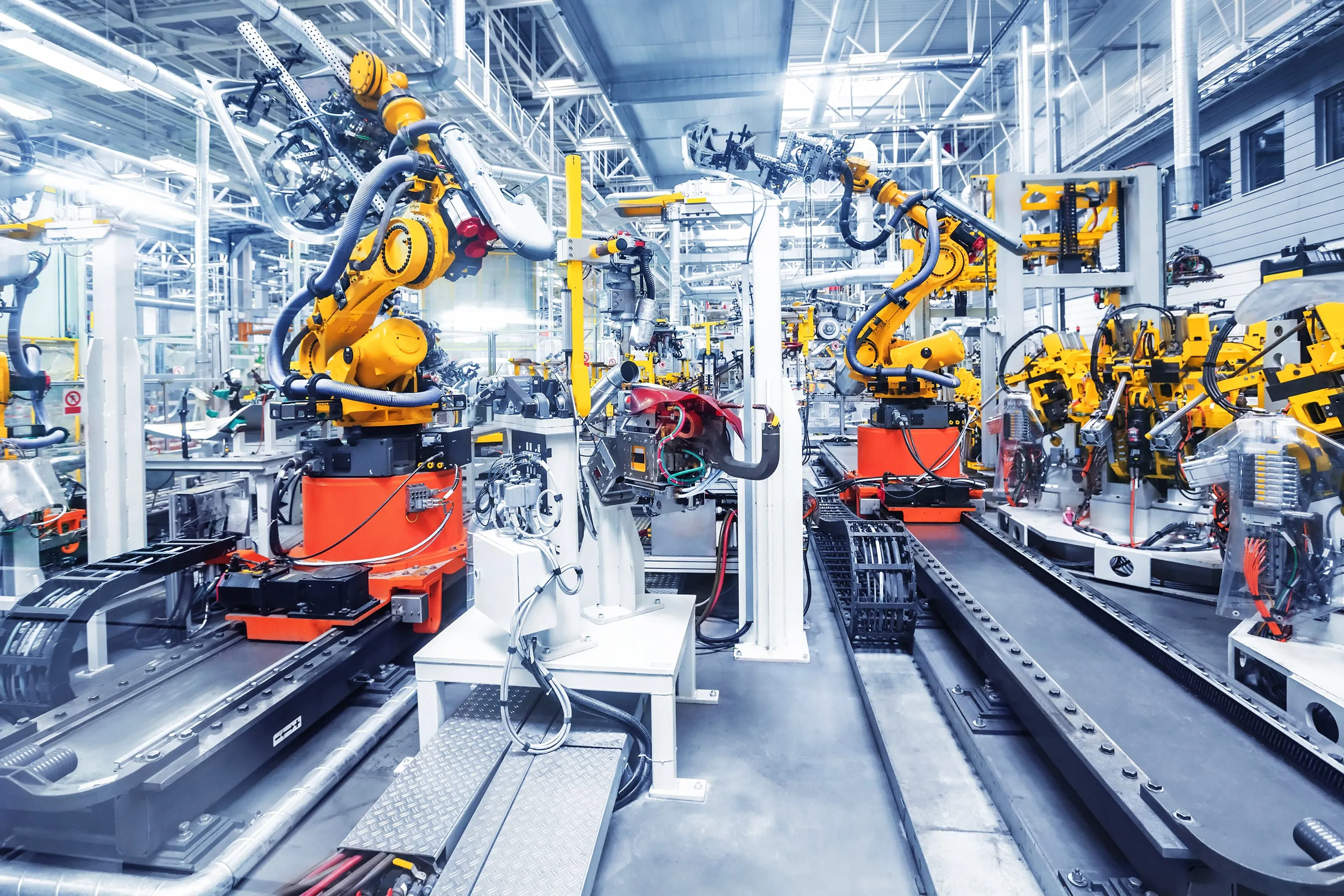 Gelbe Industrieroboter auf Linearachsen in einer automatisierten Fertigungshalle