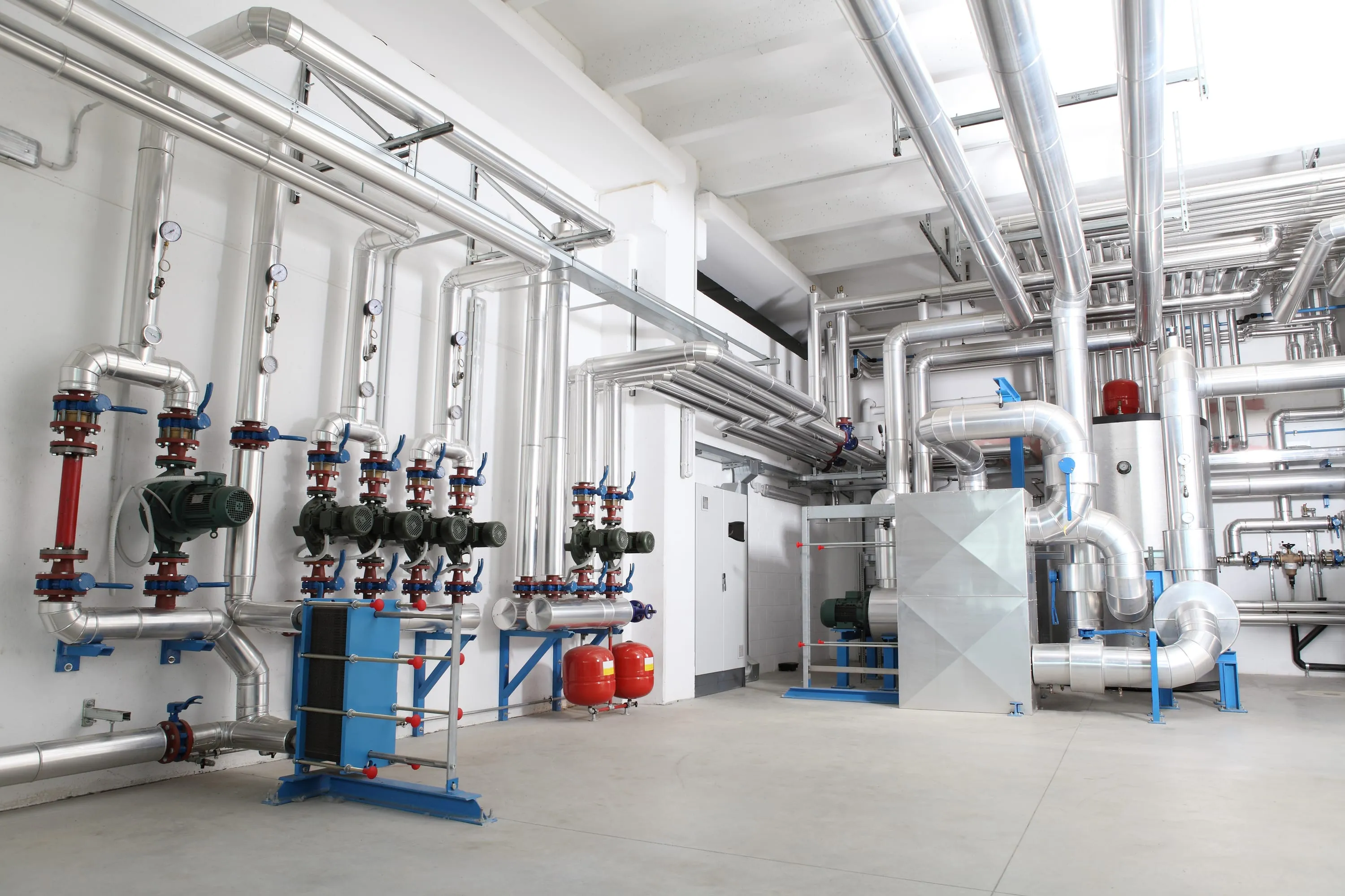 Heizzentrale mit gedämmten Rohrleitungen, Umwälzpumpen, Plattenwärmetauscher und Ausdehnungsgefäßen