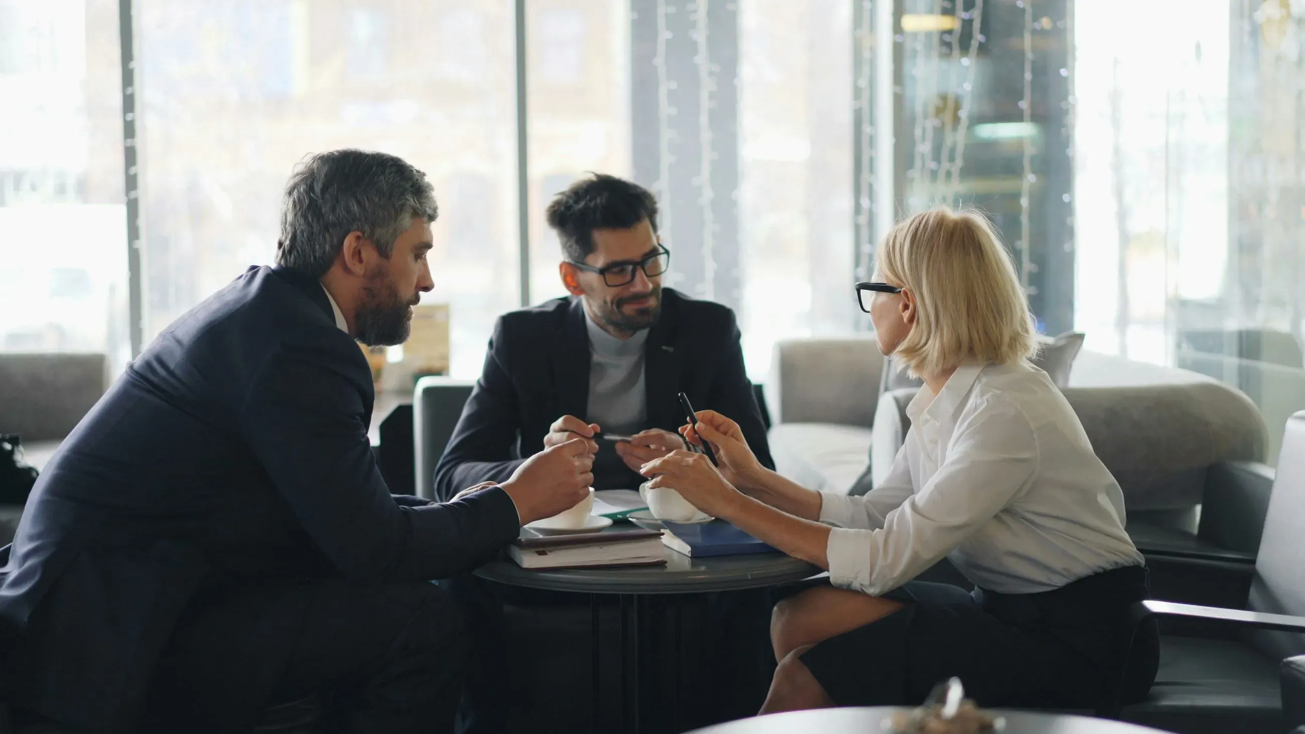 Drei Personen besprechen an einem Tisch Unterlagen und Notizen